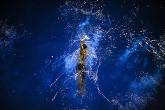 Image title:  Soar in the blue There was a diving practice, after that, the swimming coach was swimming in the pool, and I was standing in the 5m diving platform, waiting for the right moment, although the light was quiet dim, I still managed to get this one.